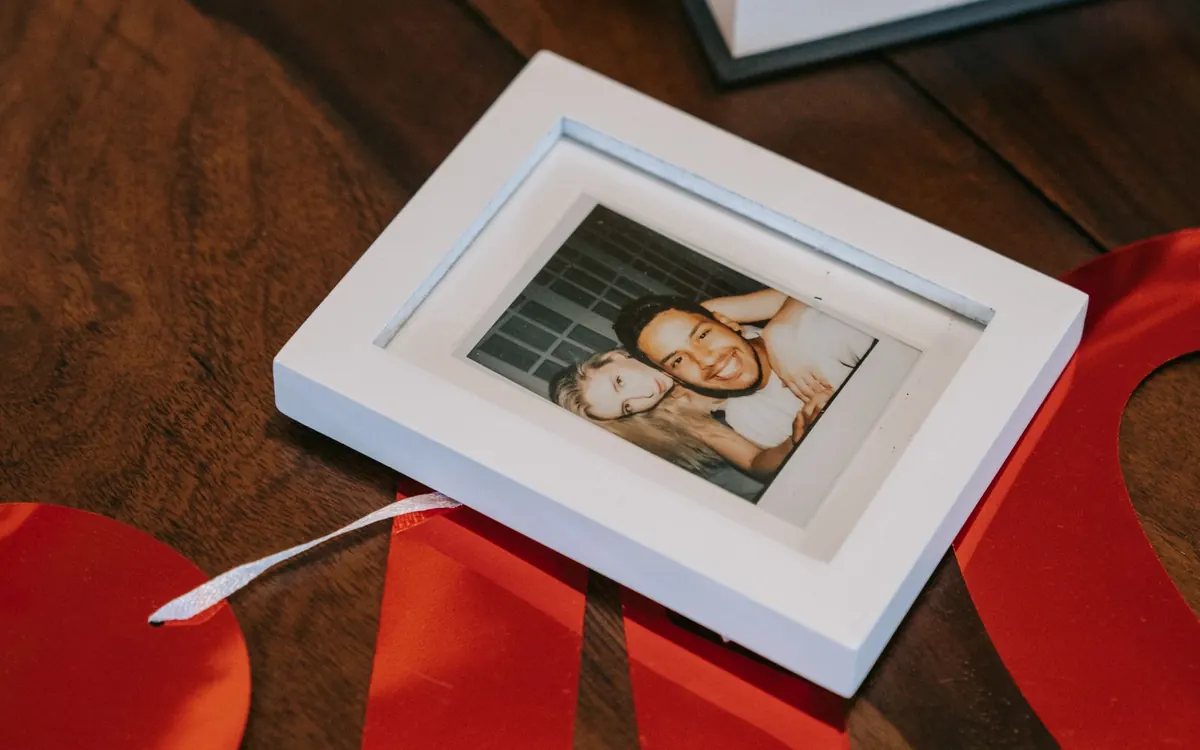 A framed couple photograph beside a wrapped gift on a wooden table.