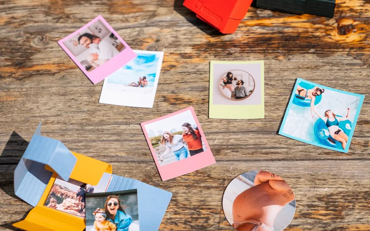 Printed instant photographs spread across a wooden desk.