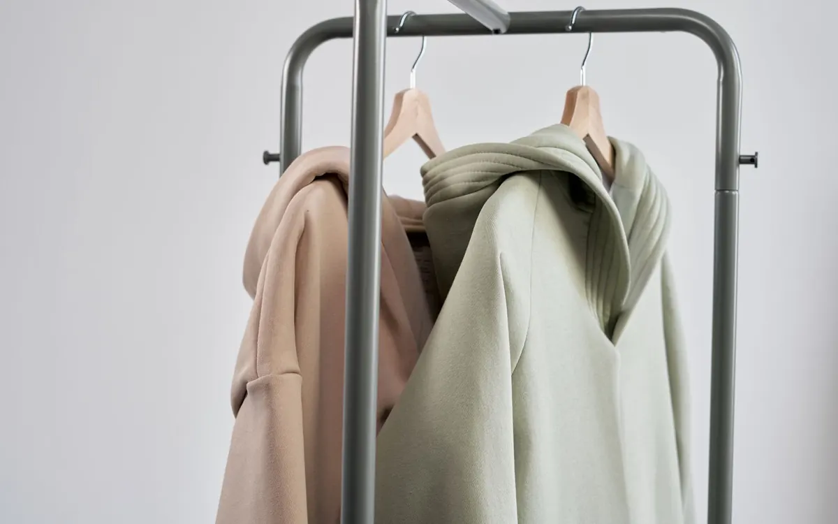 Soft green and beige hoodies hanging side by side.