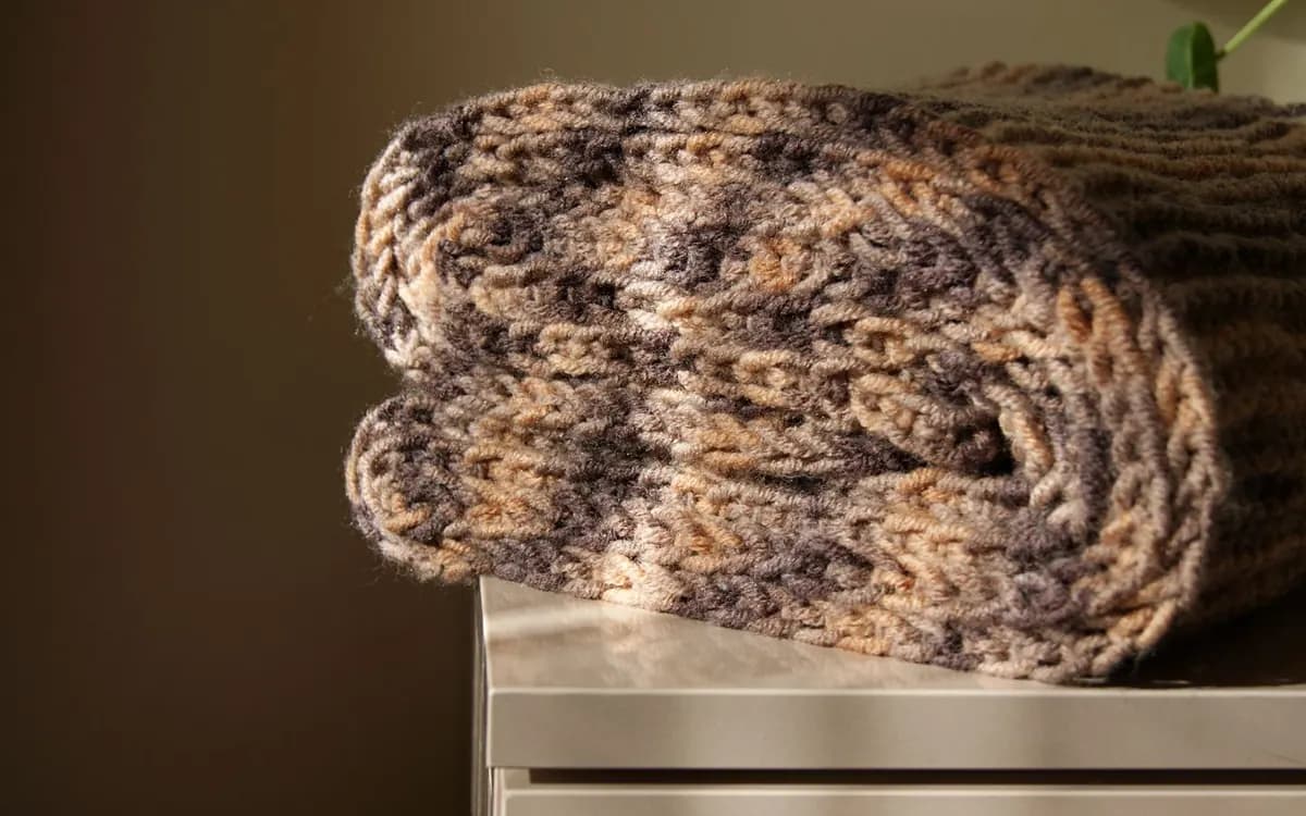 A soft knitted scarf folded neatly in warm neutral colours.