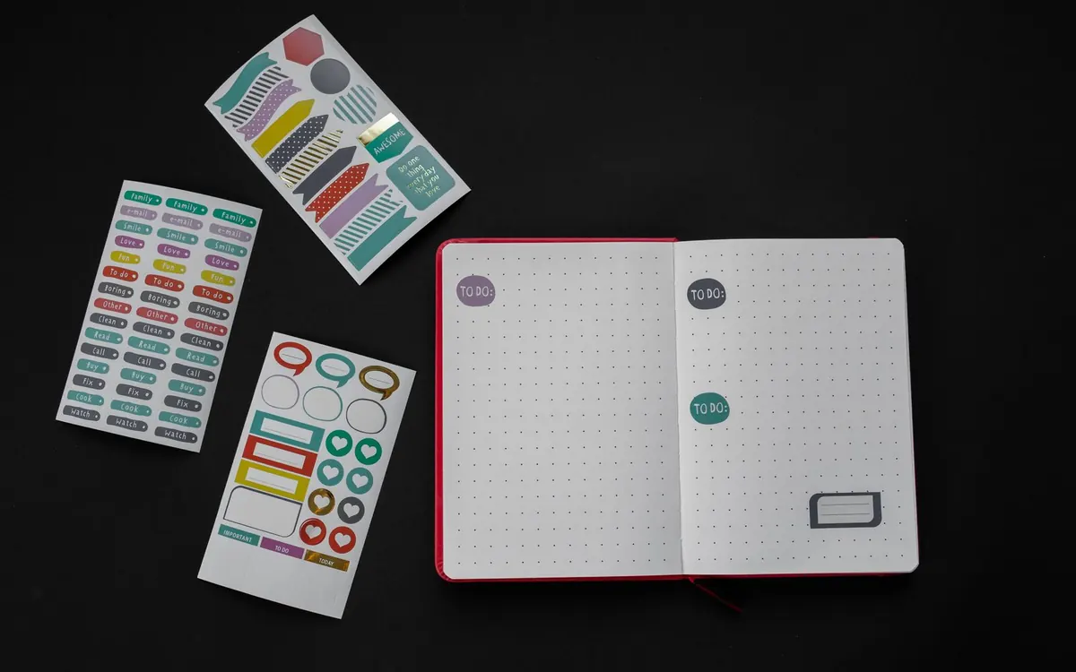 Colourful sticker sheets with hearts, labels and decorative shapes beside an open notebook.