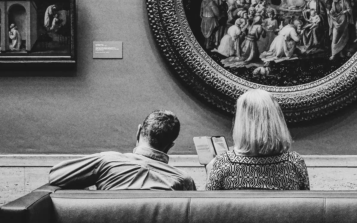 Two visitors looking at paintings in an art gallery.
