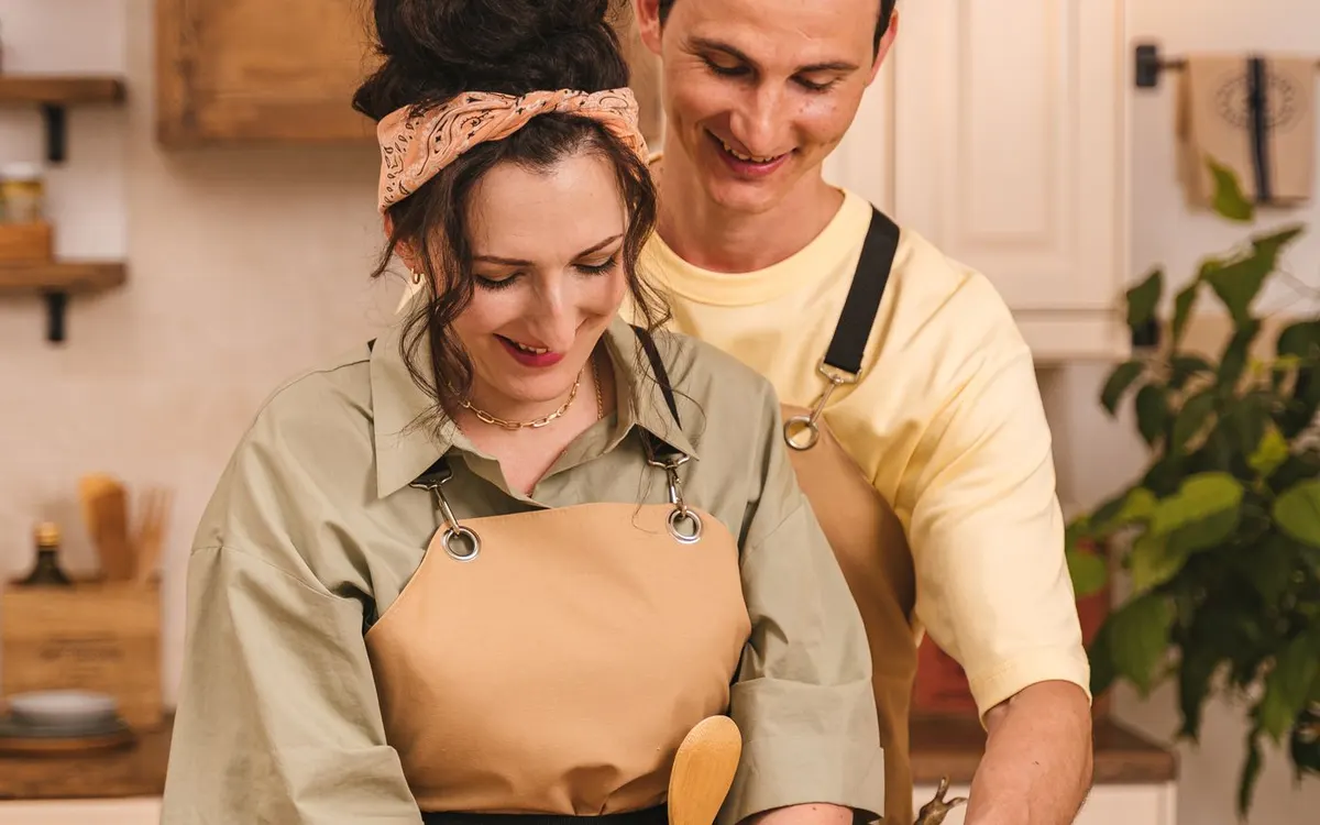 Two people preparing dough together in a kitchen.