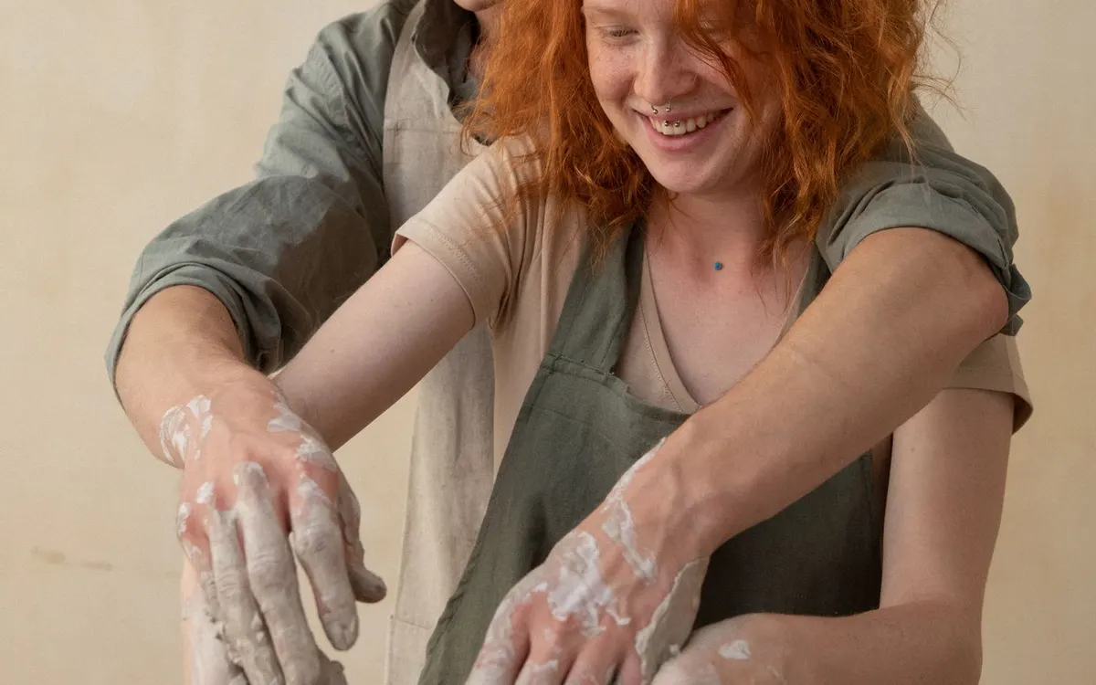 Two people shaping clay during a pottery workshop.