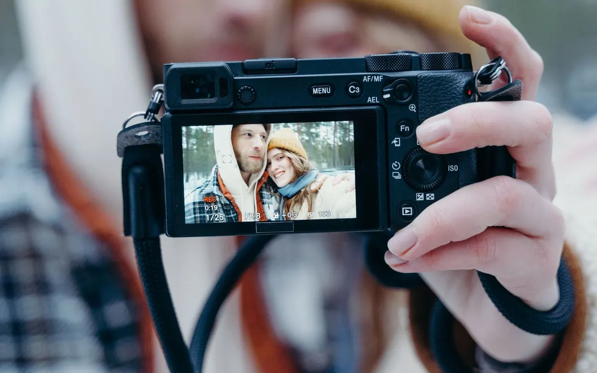 A couple taking a photograph with a camera outdoors.