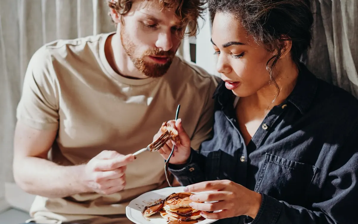 Two people sharing a pancake breakfast at home.