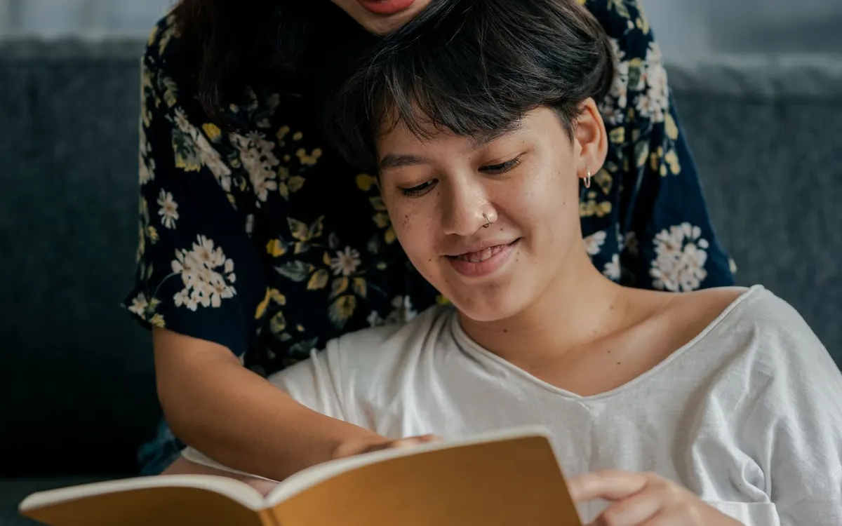 A couple reading a book together at home.