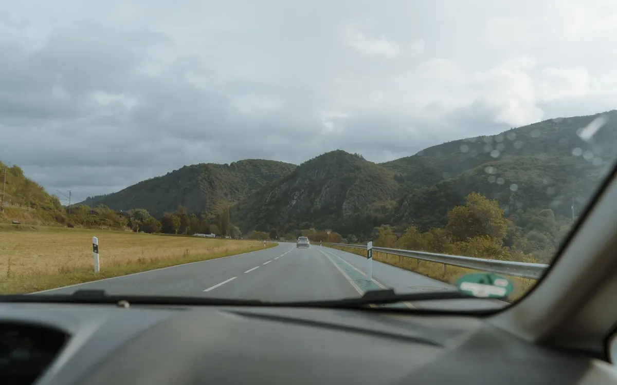 A view of a mountain road through a car window.