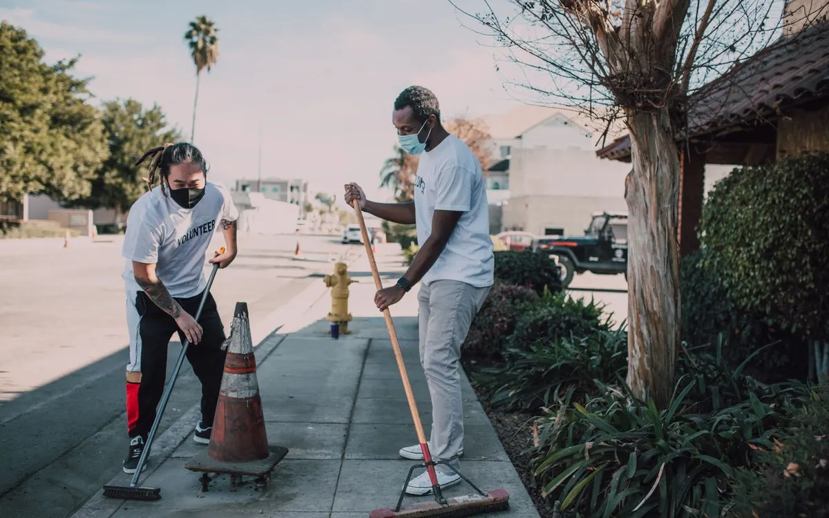 Two volunteers collecting litter during a street clean-up.