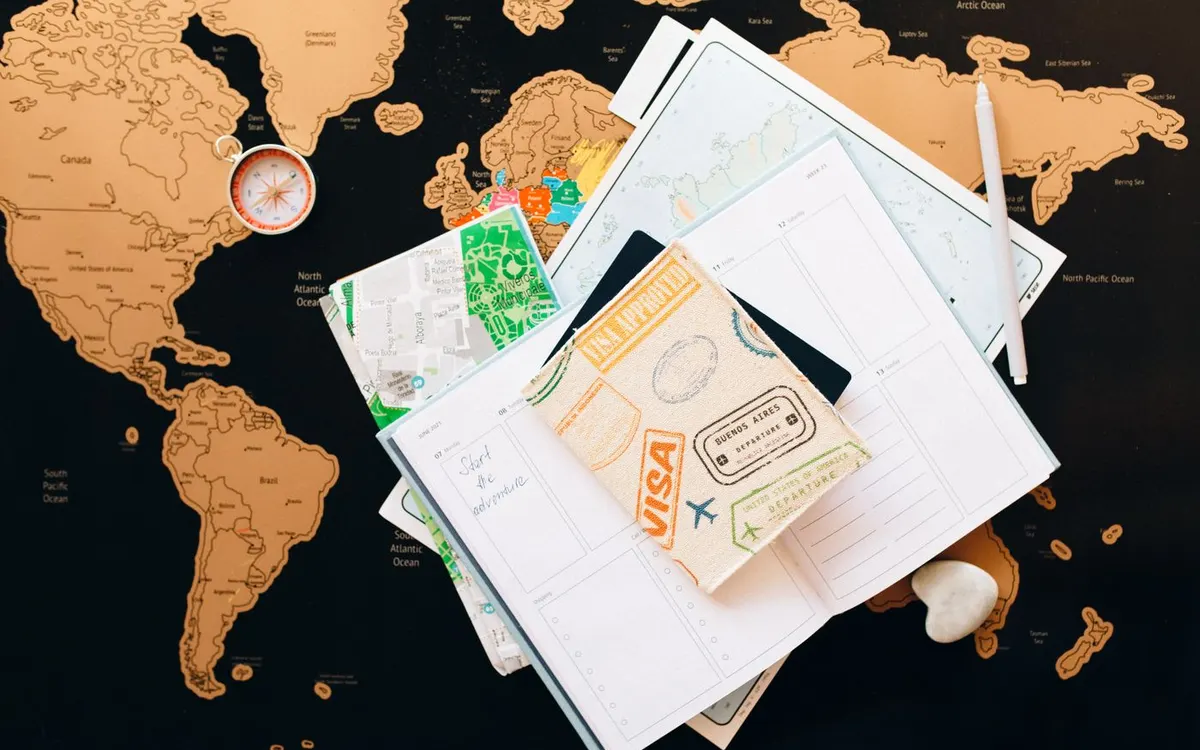 A passport and travel planning notes arranged over a map.